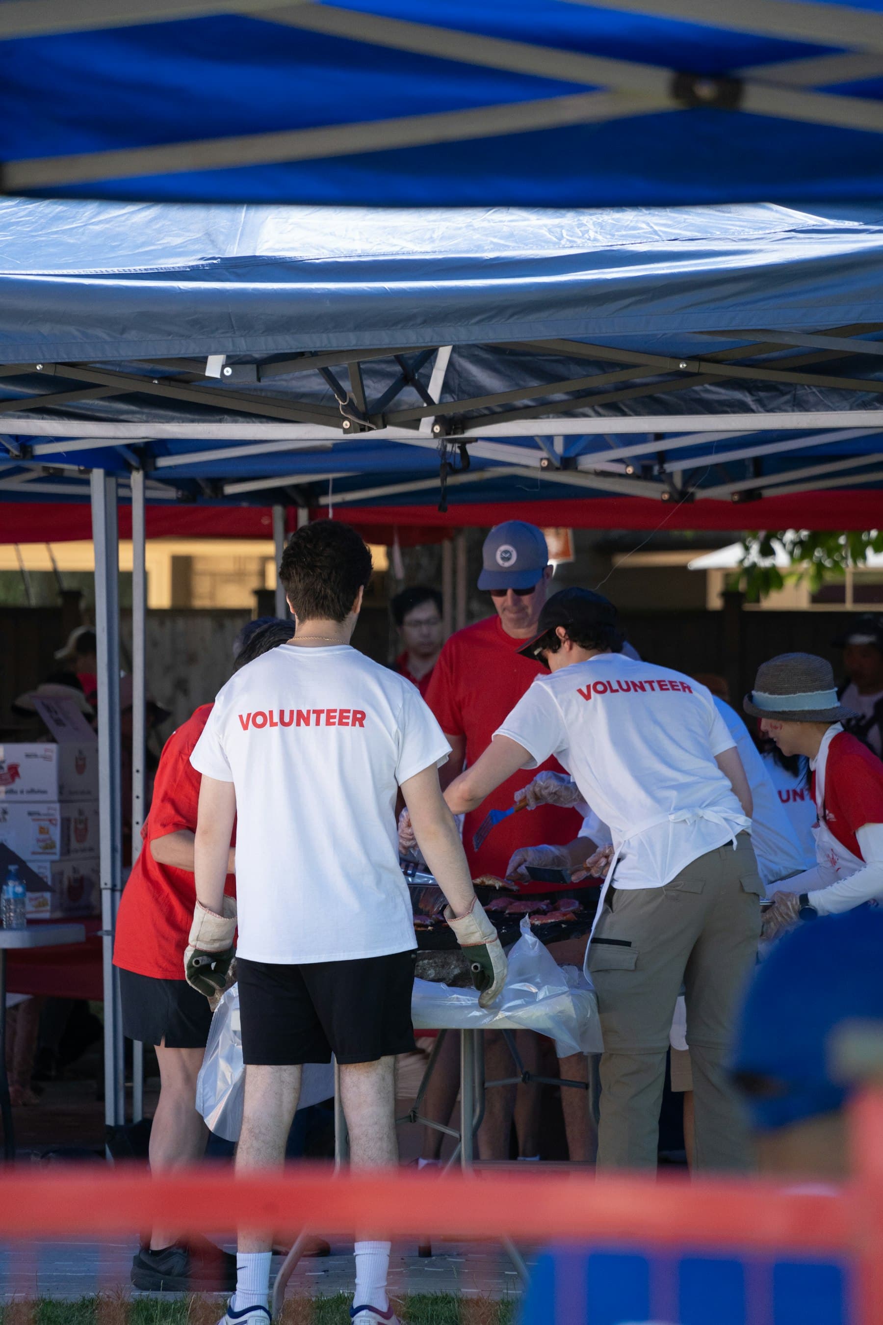 Volunteers in branded shirts serving food under an outdoor canopy